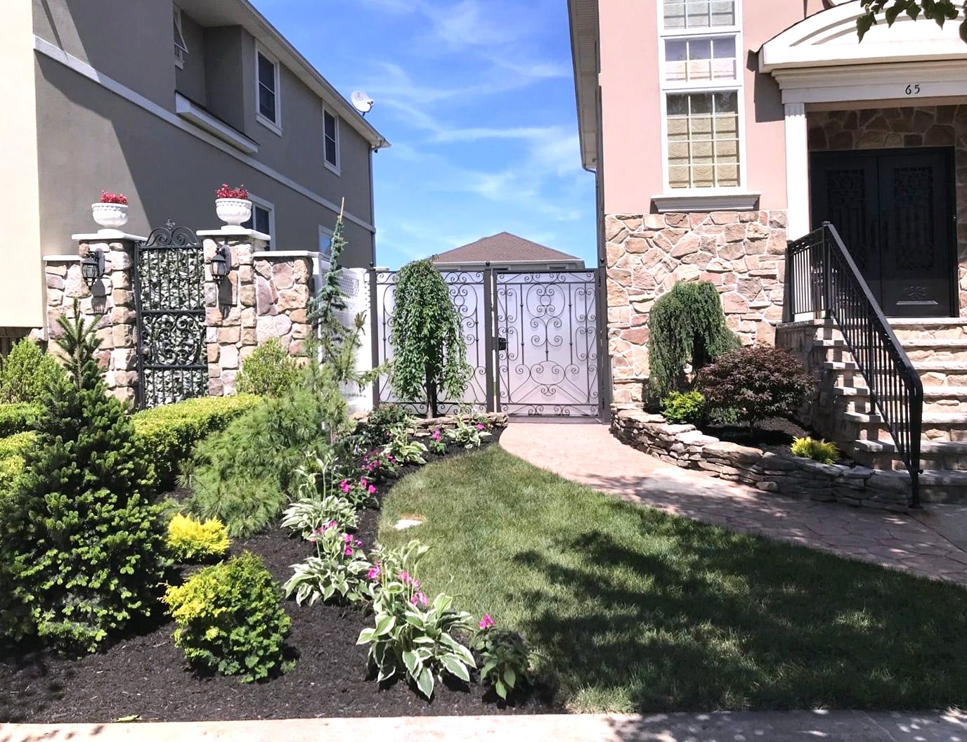 Front yard with iron gates, stone pillars, planting beds and lawn