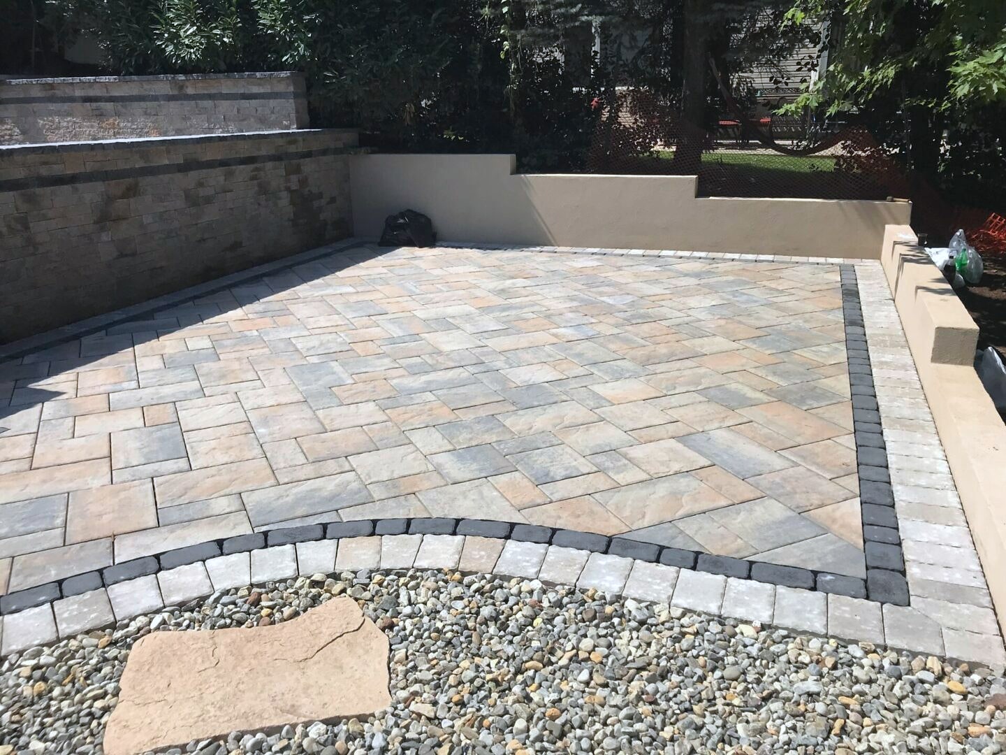 Outdoor kitchen with stainless grill and fridge on paver patio